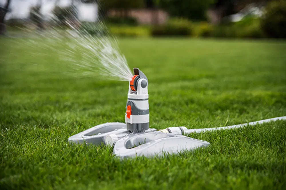 Detailansicht des Bradas WHITE LINE Sprinklers auf Standfuß mit drehbarem Kopf und Tab-Schalter zur Steuerung der Bewässerung.